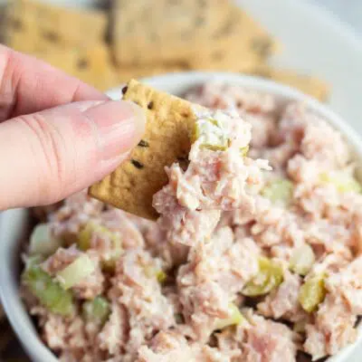 Pin image with text of cracker being dipped into ham salad.