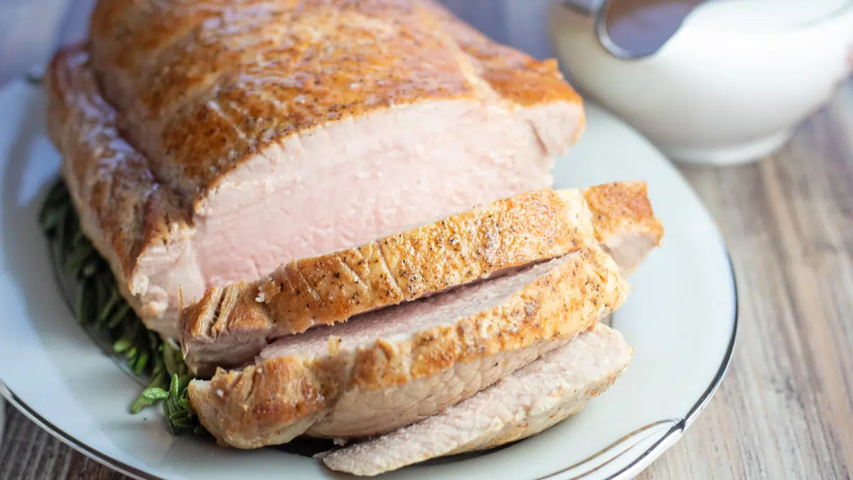 Wide image of sliced pork loin on a cutting board.