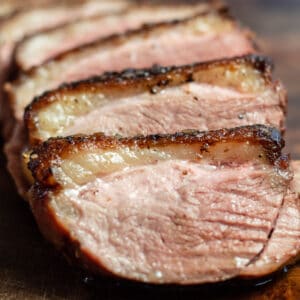 Perfectly pan seared duck breast sliced and served on wooden cutting board.