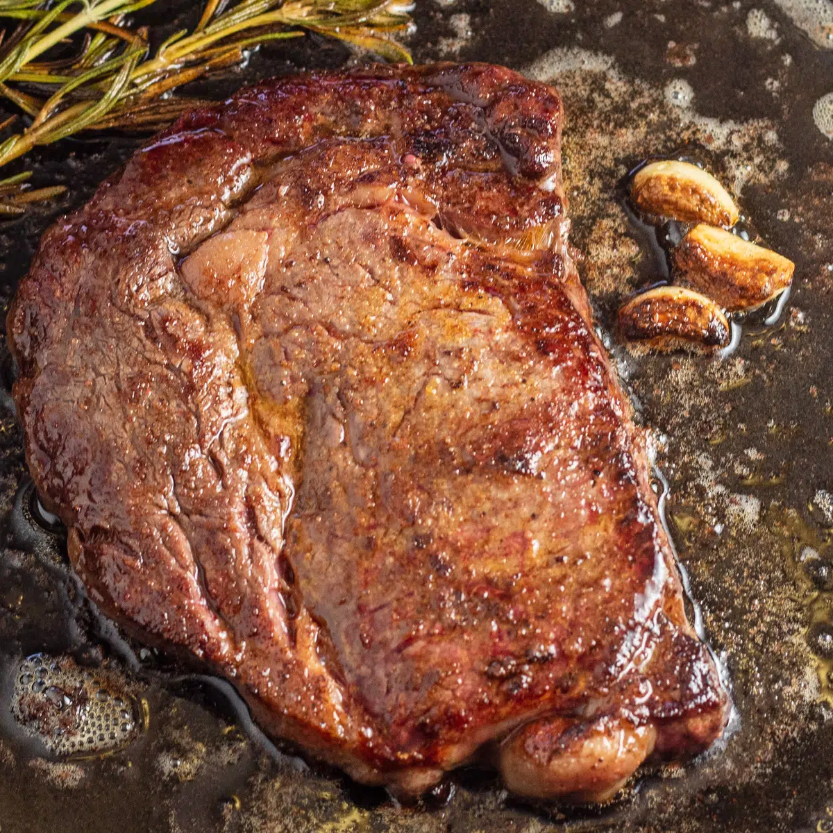 Square photo of wagyu steak in pan.