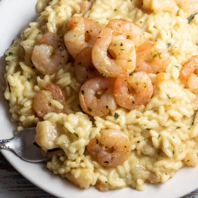 Square image of prawn risotto on a white plate.