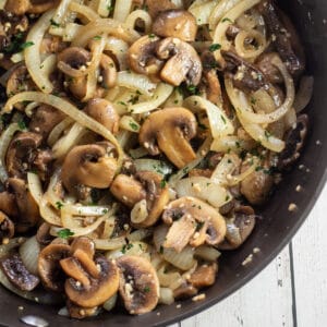 Overhead image of the suateed mushrooms and onions in dark skillet.