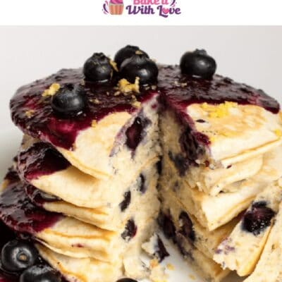 Pin image of a stack of blueberry pancakes covered in blueberry syrup.
