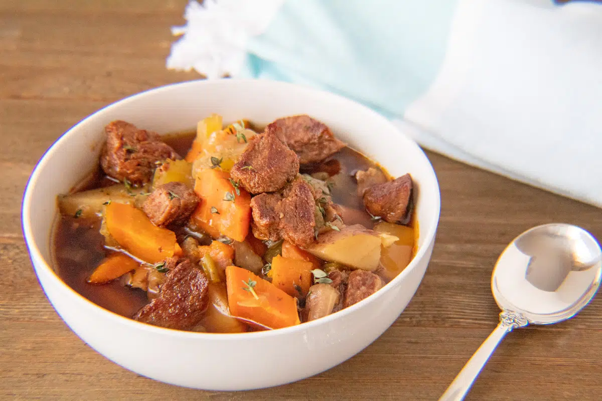 Wide image of instant pot beef stew in a white bowl.