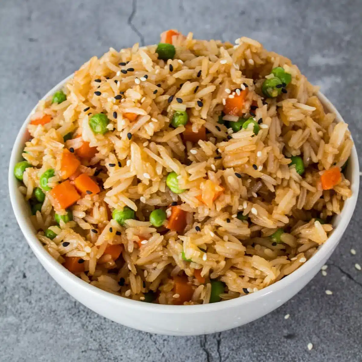 Square image of fried rice in a white bowl with a blue background.