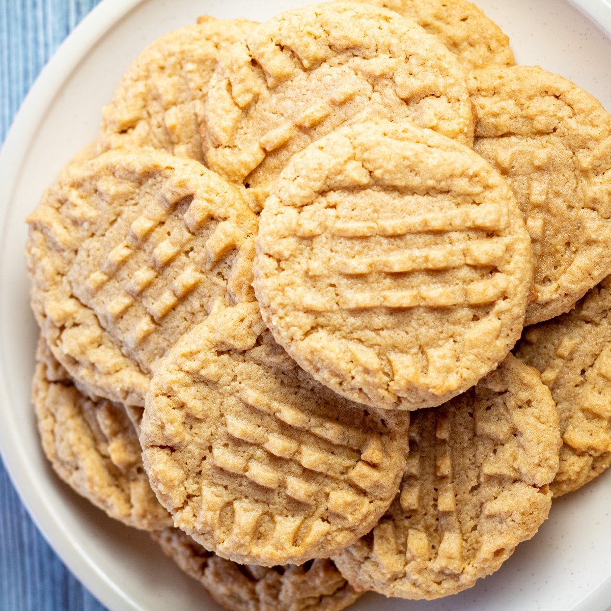 Immagine quadrata di biscotti al burro di arachidi con farina di mandorle su un piatto bianco.