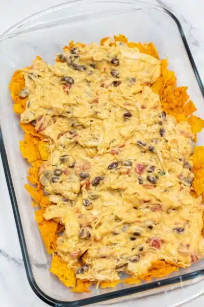 Process photo 6 adding chicken layer over crushed nacho cheese Doritos.