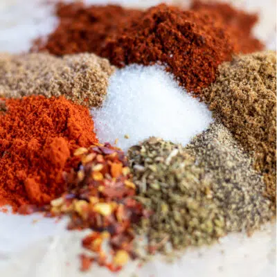 Square image of the measured out chicken taco seasoning ingredients on parchment paper.