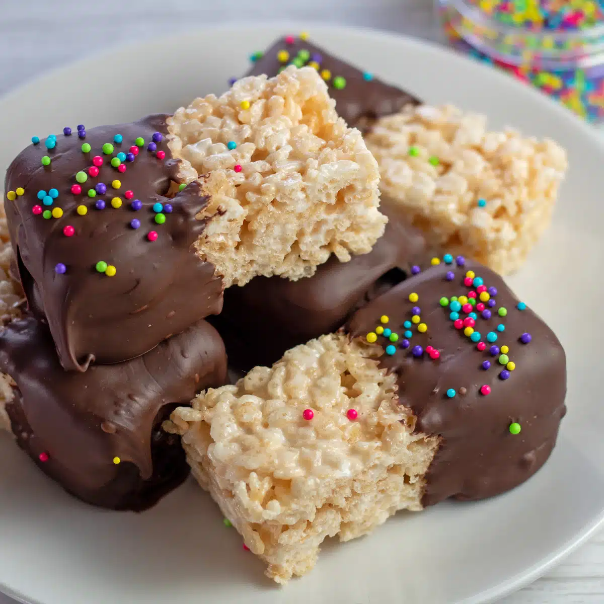Best chocolate dipped Rice Krispies treats sprinkled with nonpareils and served on plate.