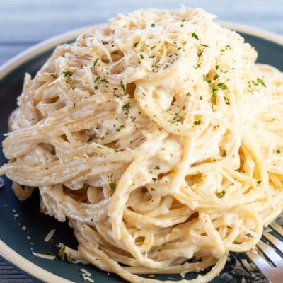 Square image of the easy cream cheese pasta served on blue plate.