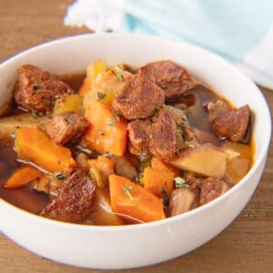 Square image of the slow cooker crockpot beef stew in white bowl.