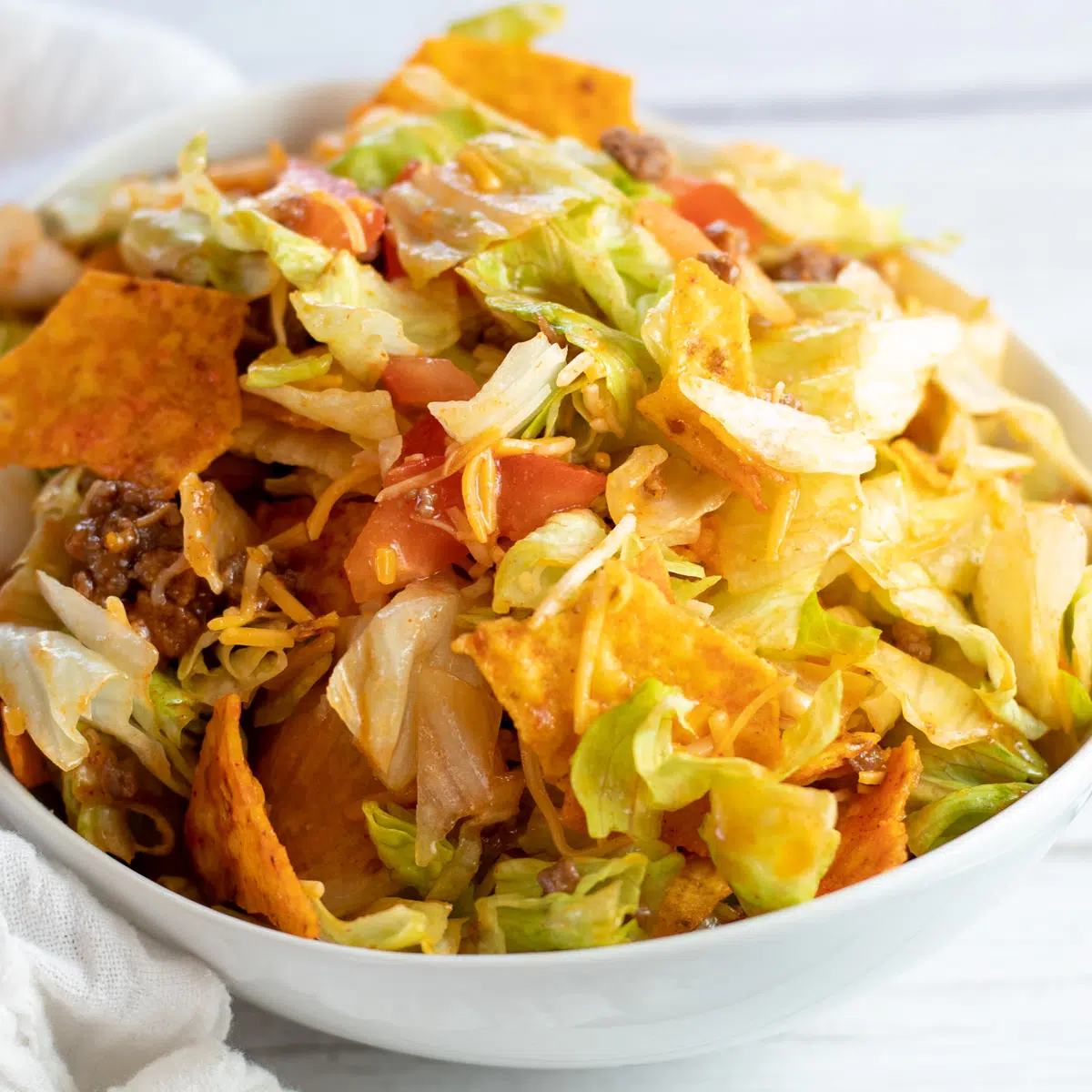 Čtvercový obrázek taco salátu Doritos v bílé misce.