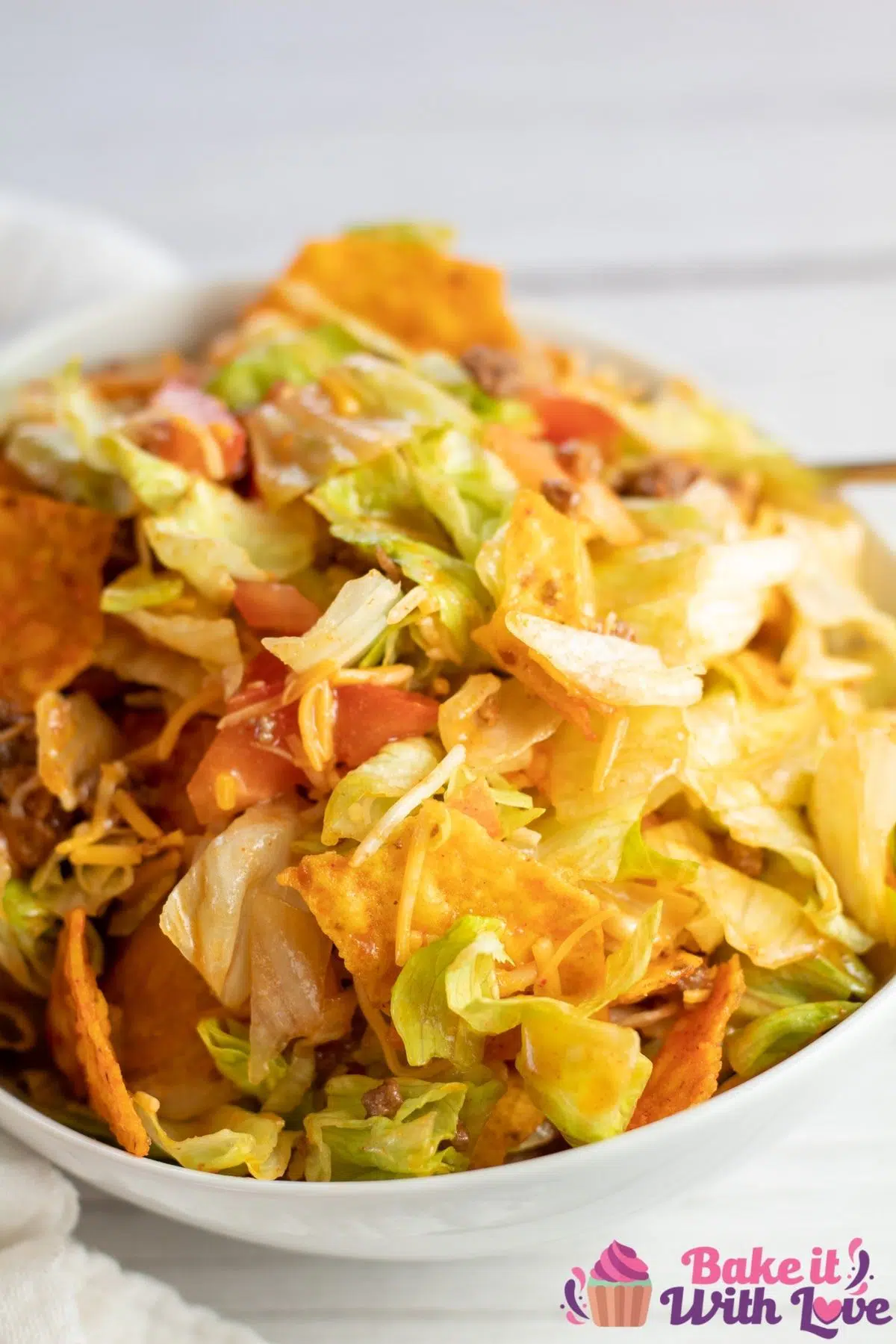 Tall image of Doritos taco salad in a white bowl.