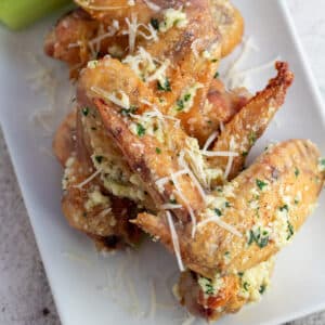 As melhores asas de frango assadas com alho parmesão servidas com bastante queijo parmesão fresco.