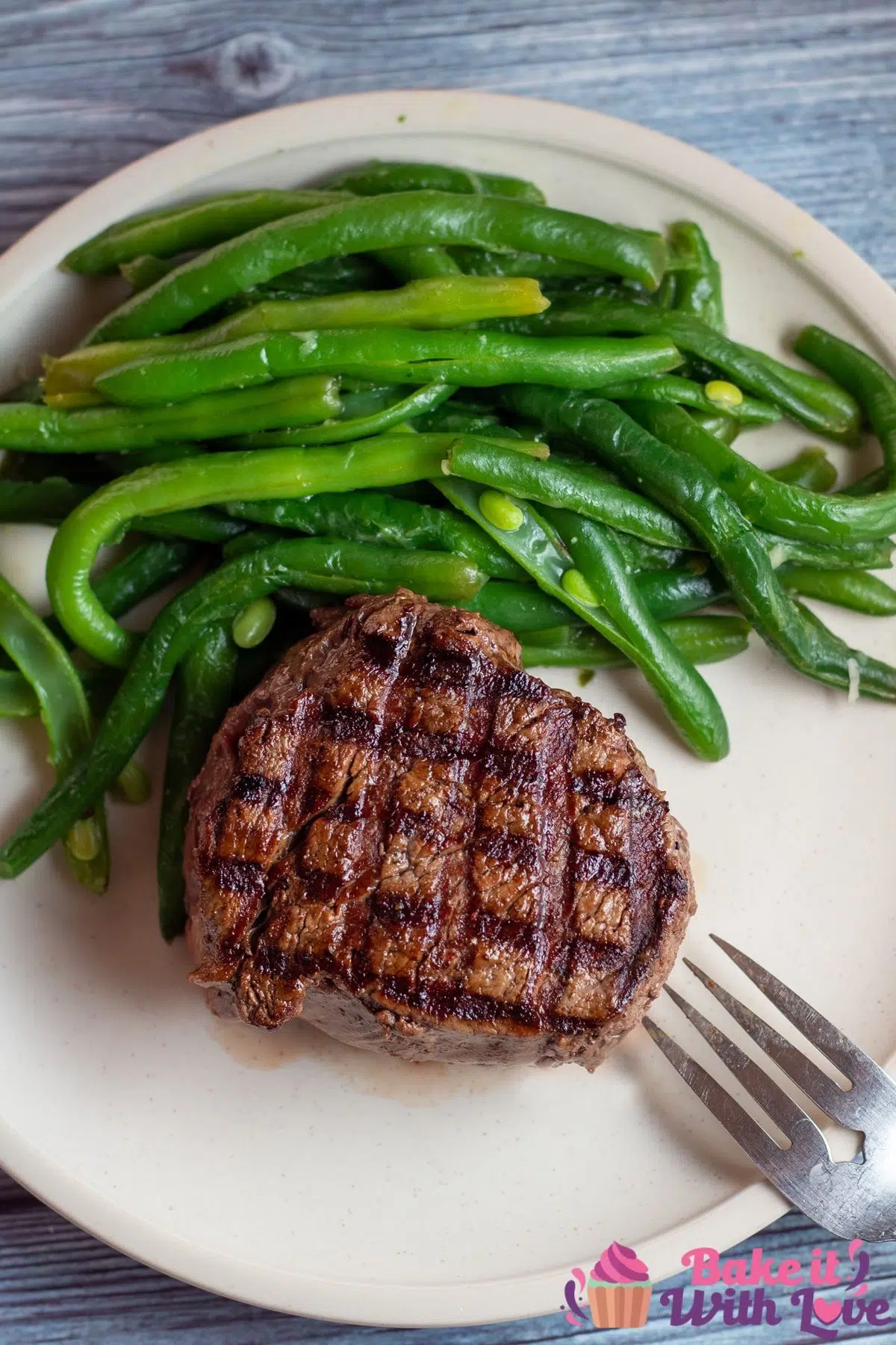 Tall image of grilled filet mignon on a plate with green beans.