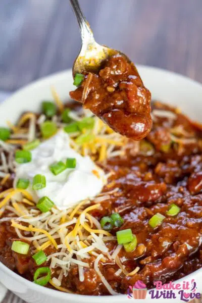 Tall image of the ground venison chili being spooned after serving.
