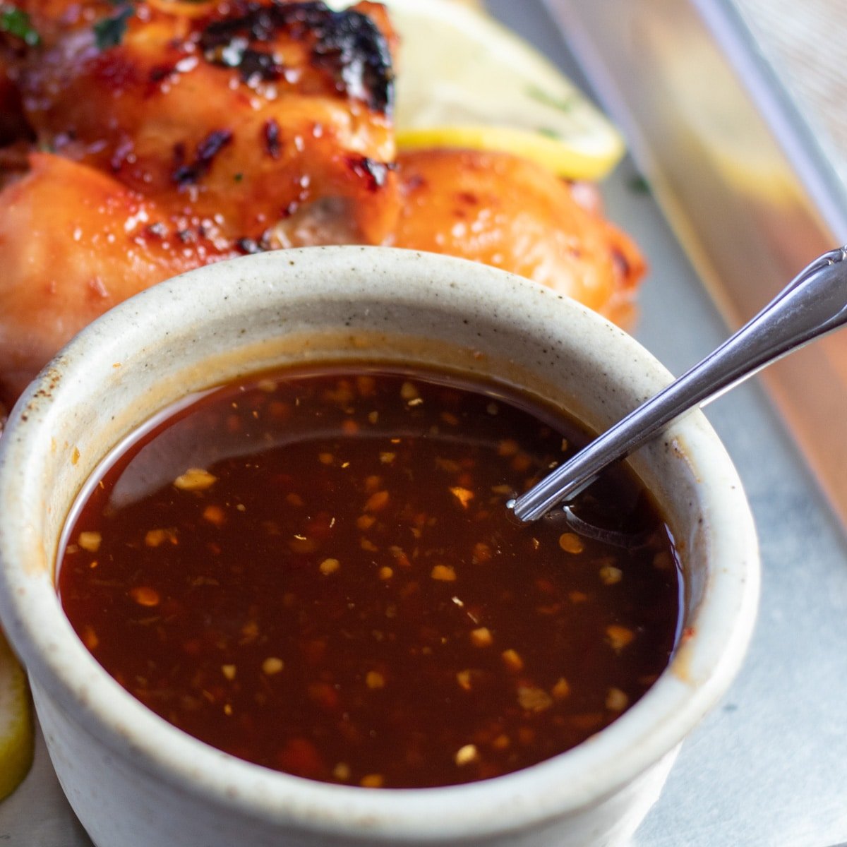 Immagine quadrata della salsa barbecue hawaiana in una piccola ciotola con un cucchiaio.