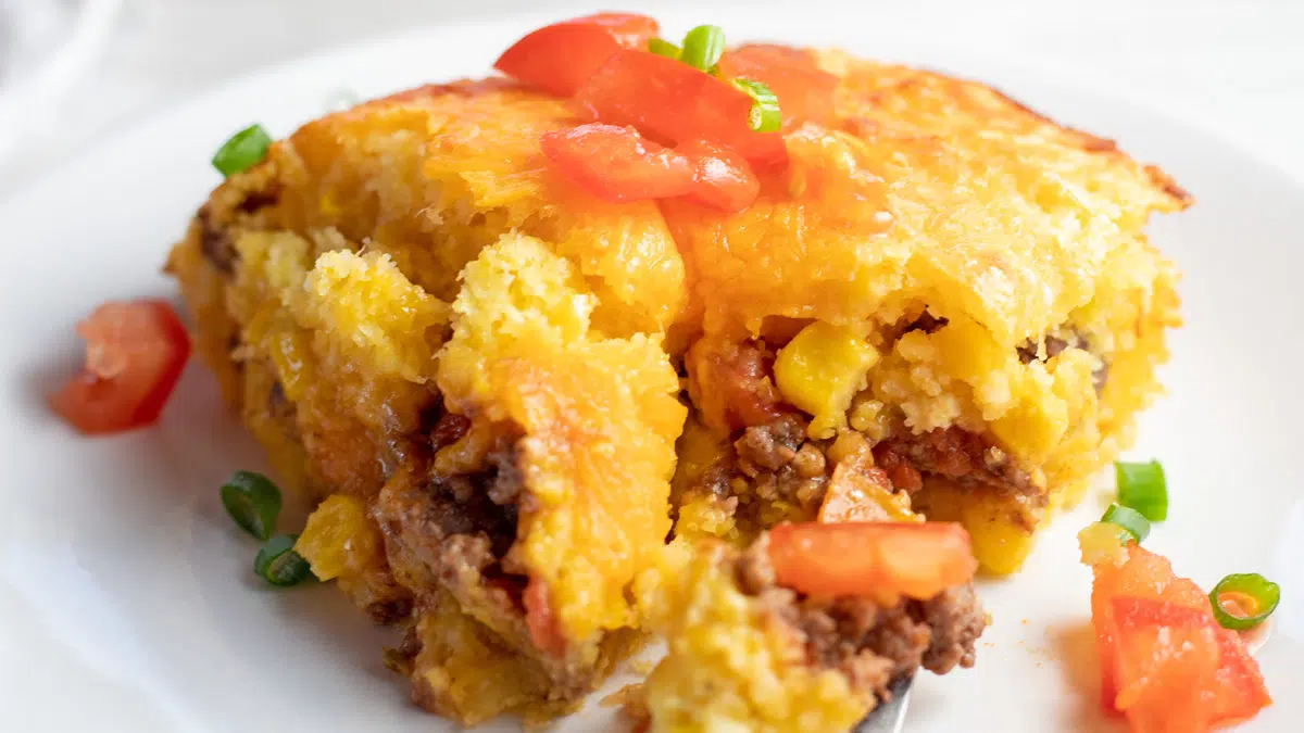 Wide closeup image of the Mexican cornbread casserole served on white plate.