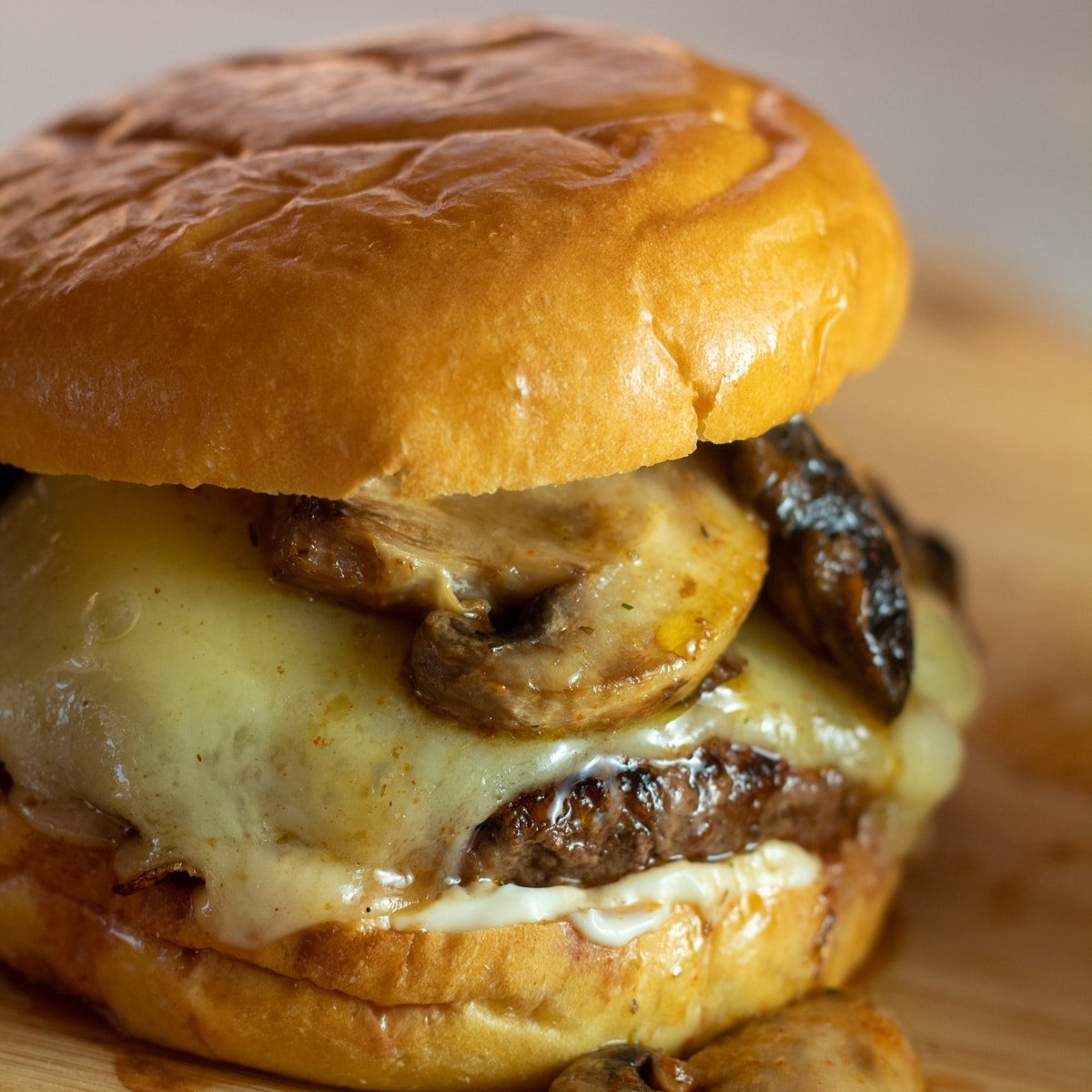 Immagine quadrata di un gustoso hamburger svizzero di funghi con funghi saltati teneri e formaggio svizzero fuso.