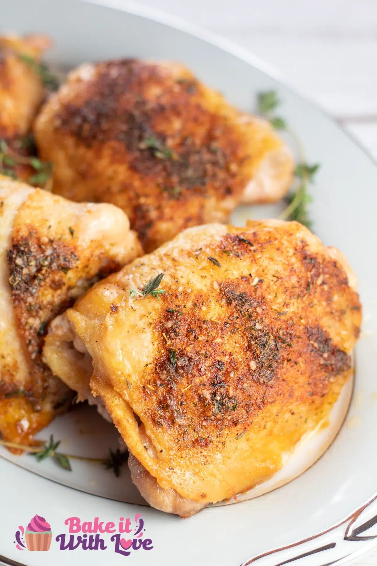 Tall image of oven baked chicken thighs on a white serving plate.