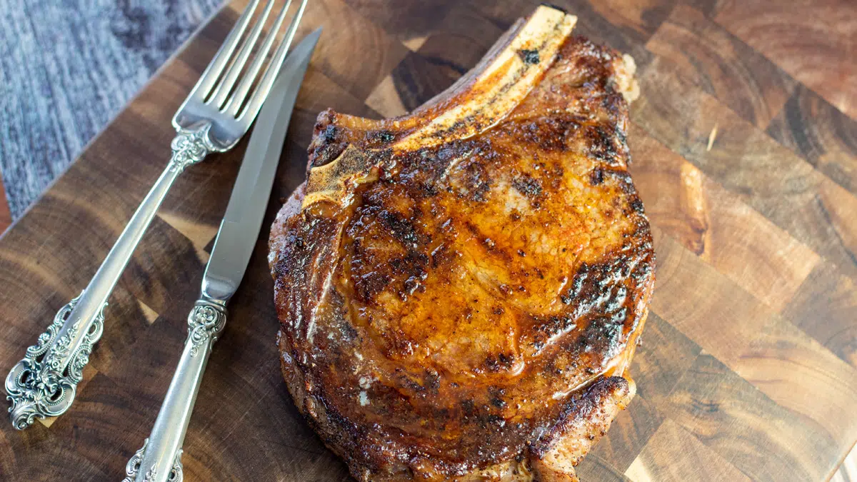 Wide image of the better than steakhouse pan seared cowboy ribeye steak on cutting board.