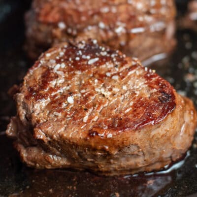 Best pan seared filet mignon steak salted and shown in cast iron skillet.