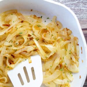Quick and easy sauteed onions in white skillet with white spatula.