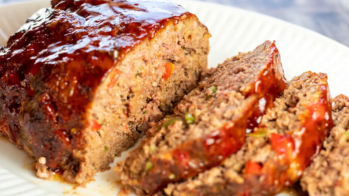 Wide image of the sliced sweet and sour meatloaf on white platter.