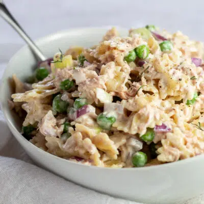 Best tuna salad with pasta served in white bowl on light background.