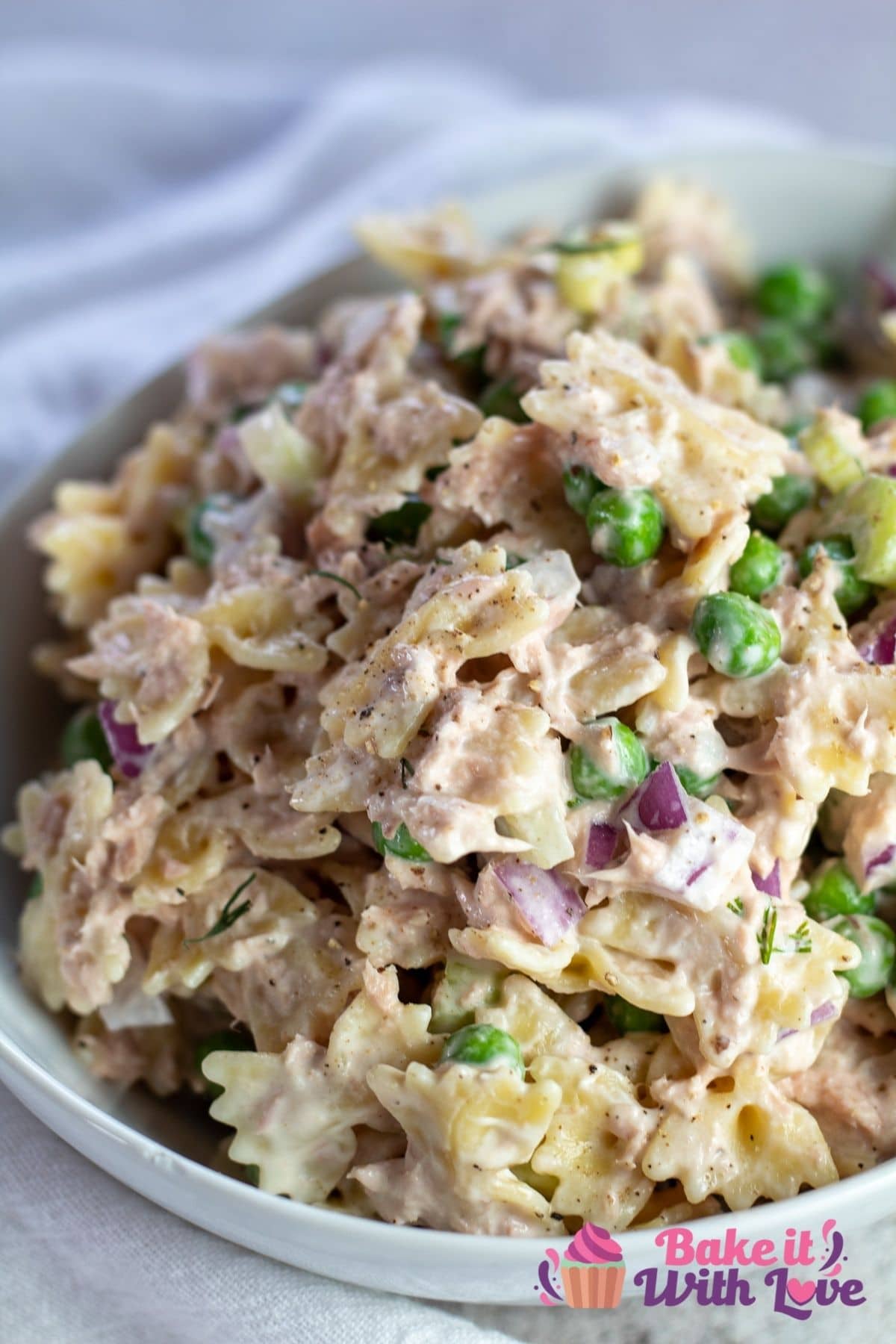 Tall image of the tuna salad with pasta in white bowl.