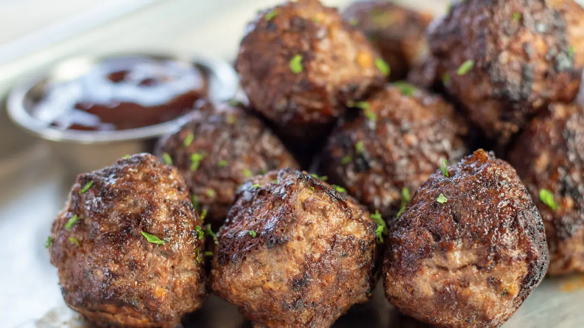 Wide closeup on the stacked venison meatballs on metal rimmed baking sheet.