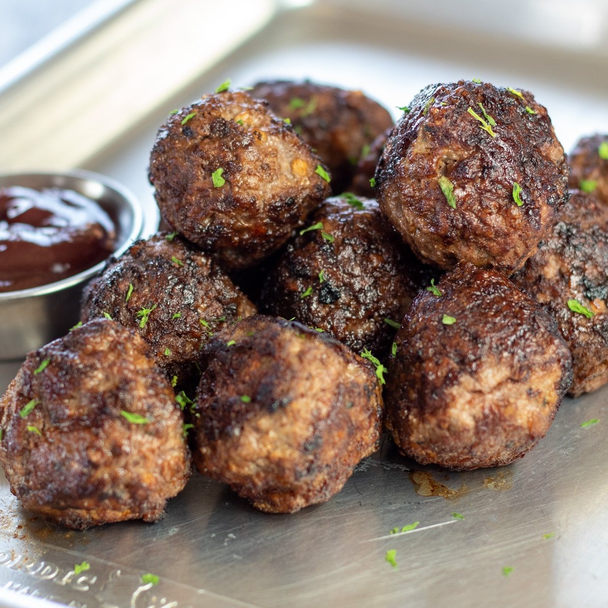 Las mejores albóndigas de venado se sirven en una bandeja de metal con salsa para mojar.