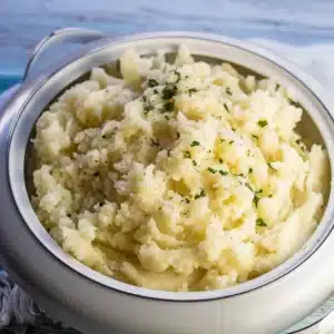 Square image of mashed potatoes in a white bowl.