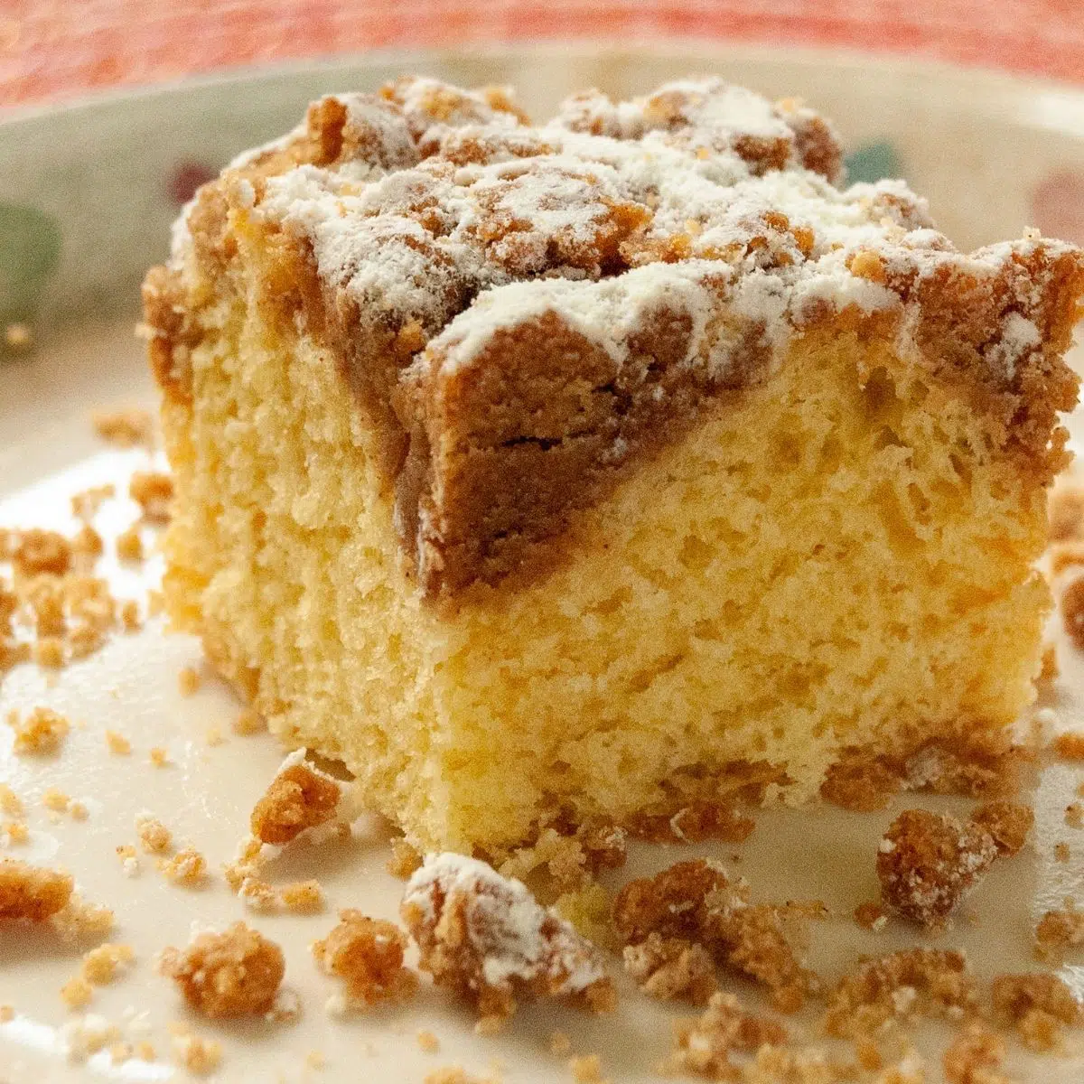 A generous slice of Bisquick coffee cake on plate with crumbs.