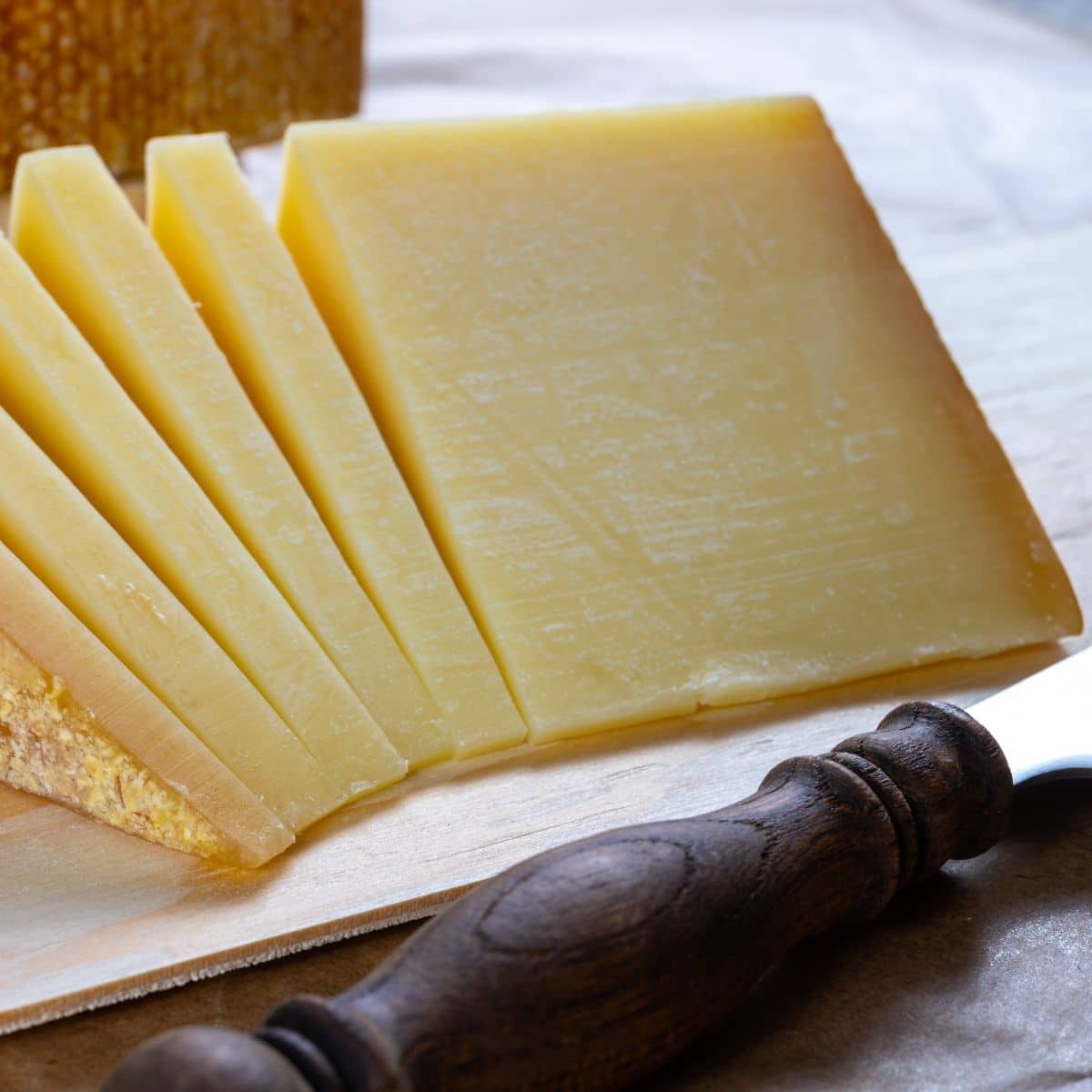 As melhores opções de substitutos de queijo gruyère com imagem de gruyère fatiado na hora.