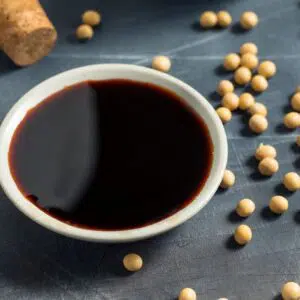 Tamari vs soy sauce image showing a white bowl with tamari sauce on grey background.