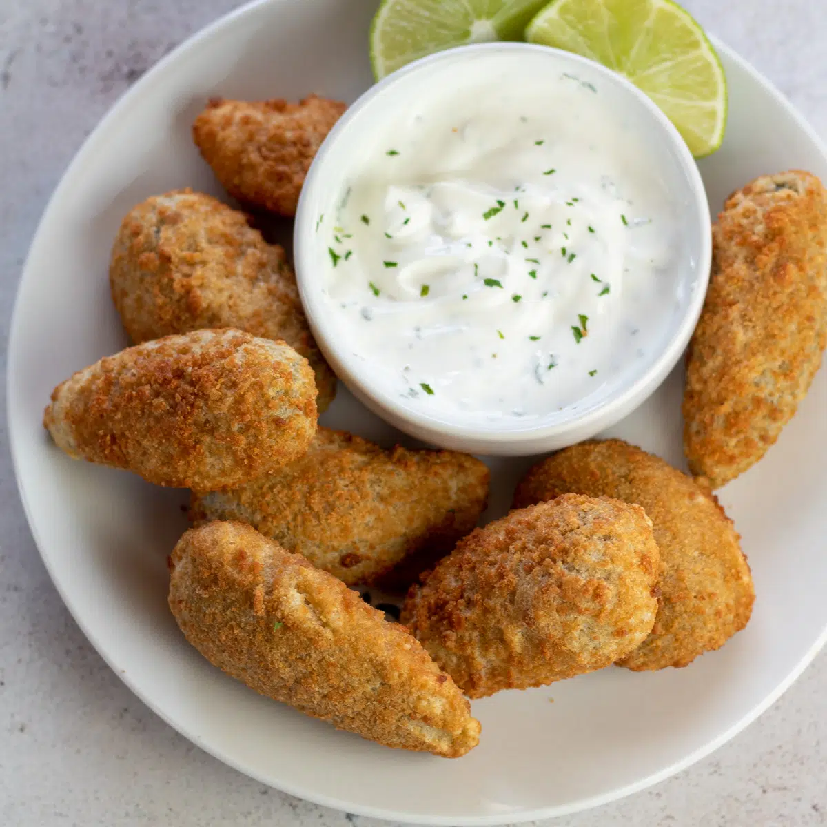 Poppers de jalapeno congelados da fritadeira de ar fritos à perfeição crocante dourada e servidos na chapa branca.