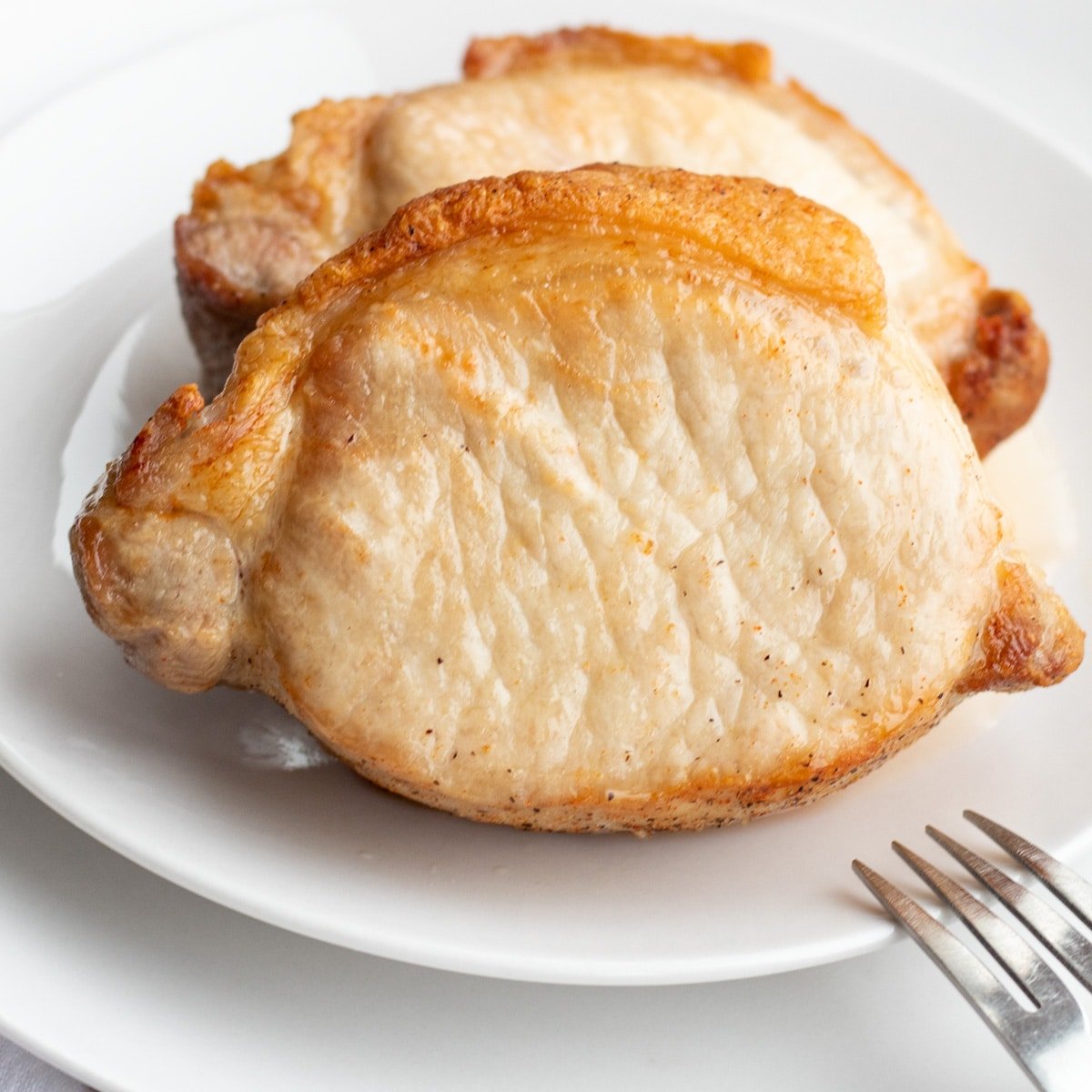 Meilleures côtelettes de longe de porc friteuse à air servies sur une assiette blanche.
