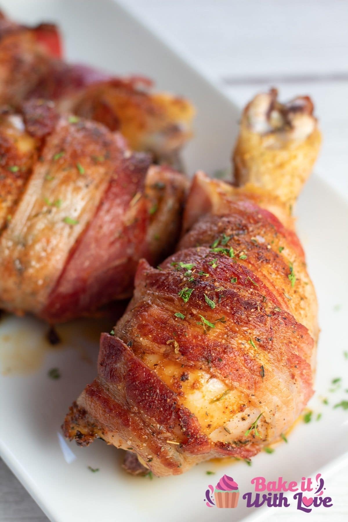 Tall closeup on a bacon wrapped baked chicken drumstick.