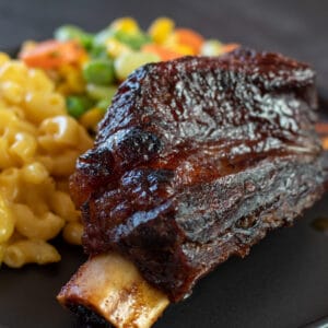 Square image of baked bbq short ribs plated with mac and cheese.