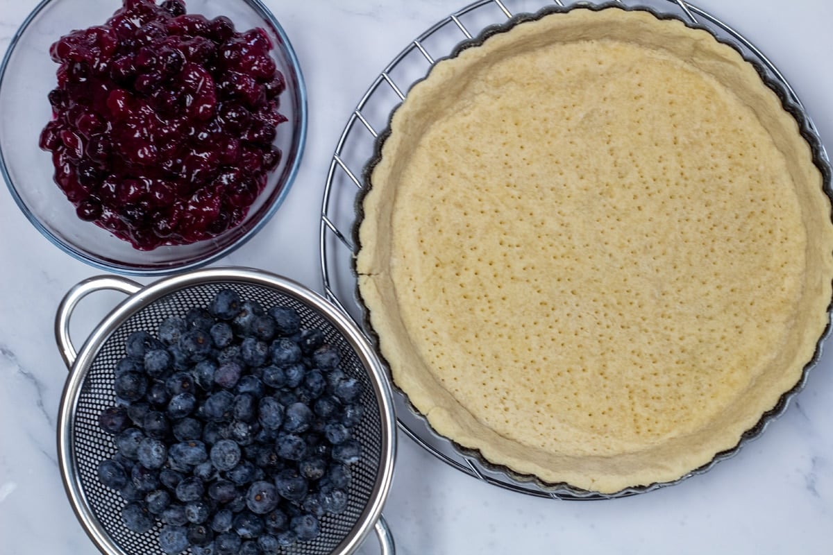 Ingredient photo showing tart crust, blueberry filling, and fresh blueberries.