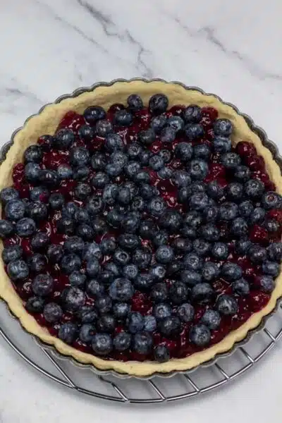 Process image 9 showing unbaked tart with filling and fresh blueberries.