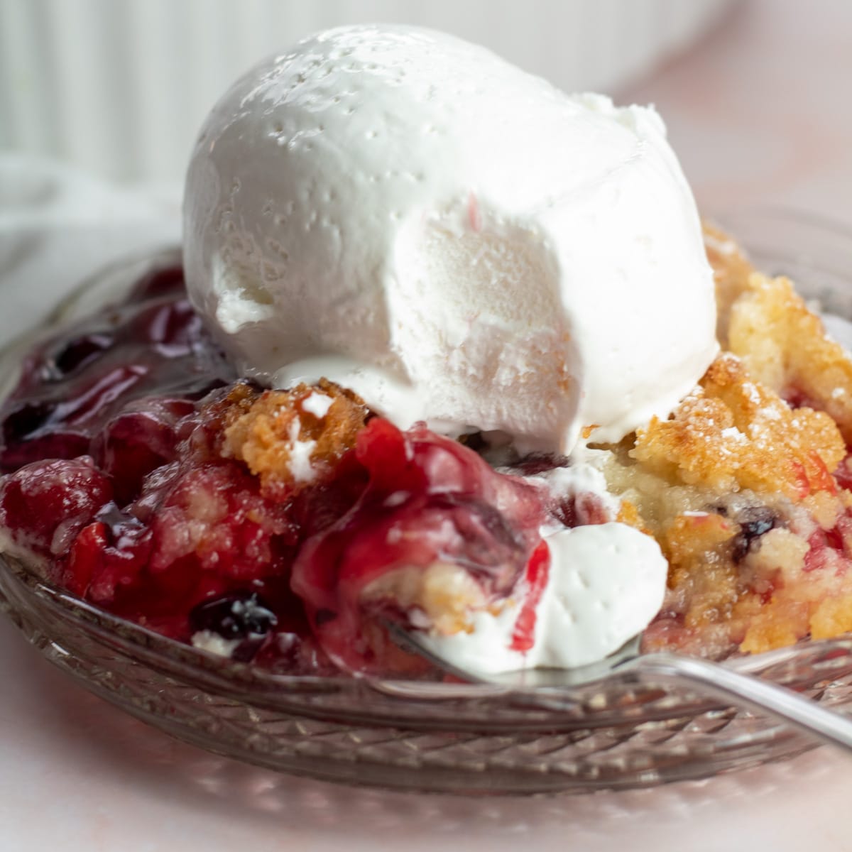 O melhor bolo de cereja de mirtilo já servido em prato de vidro com sorvete.