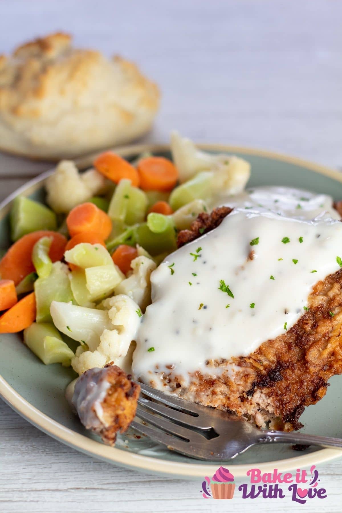 Tall image of chicken fried cube steak on a plate with vegetables.