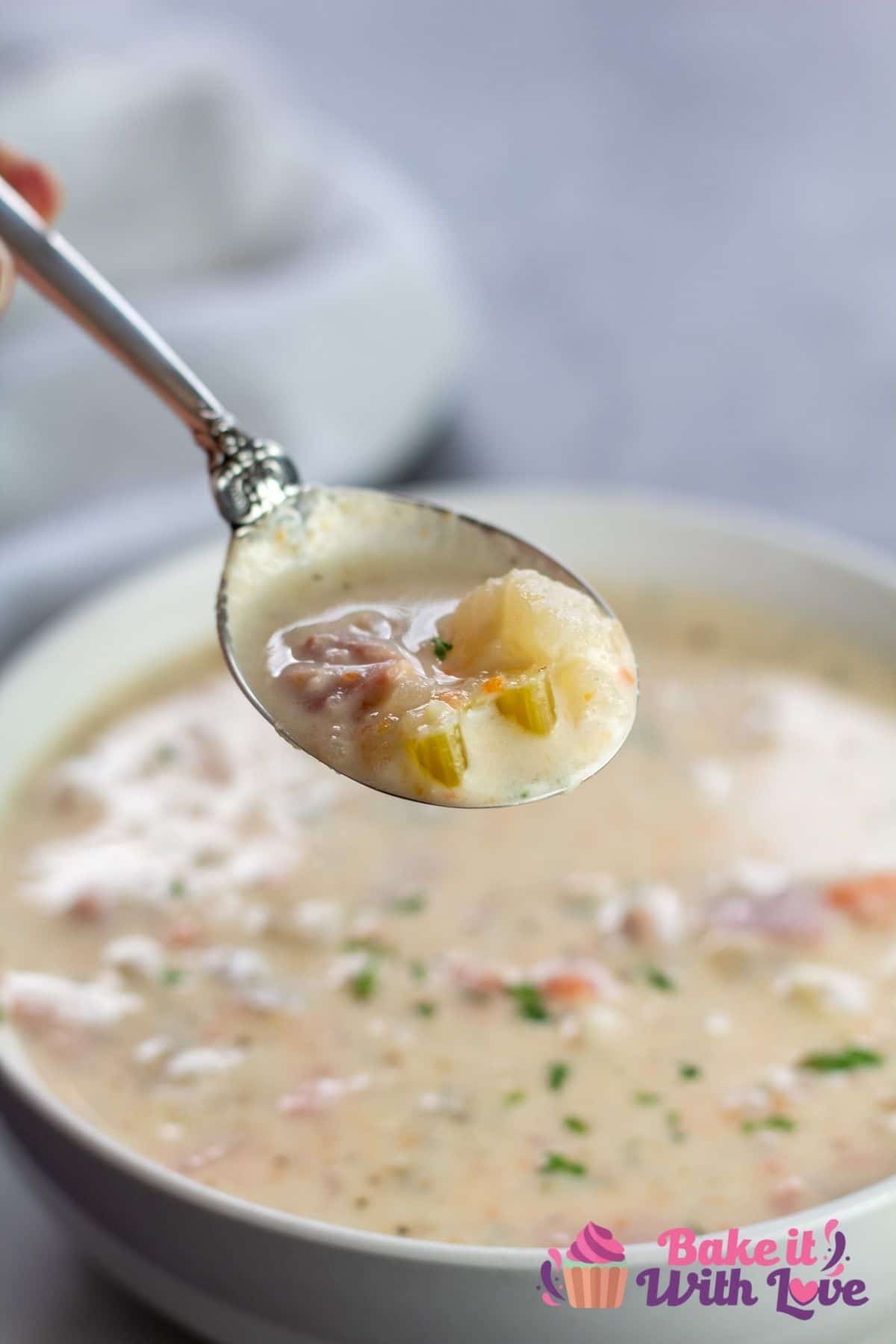 Tall image of the crockpot creamy ham potato soup being spooned out of bowl.