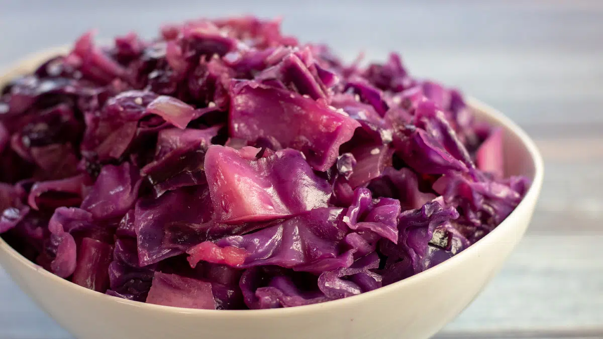 Wide image of a white bowl of braised red cabbage.