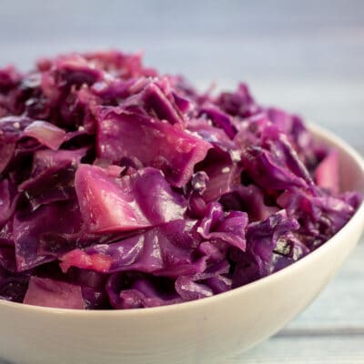 Square image of a white bowl of braised red cabbage.