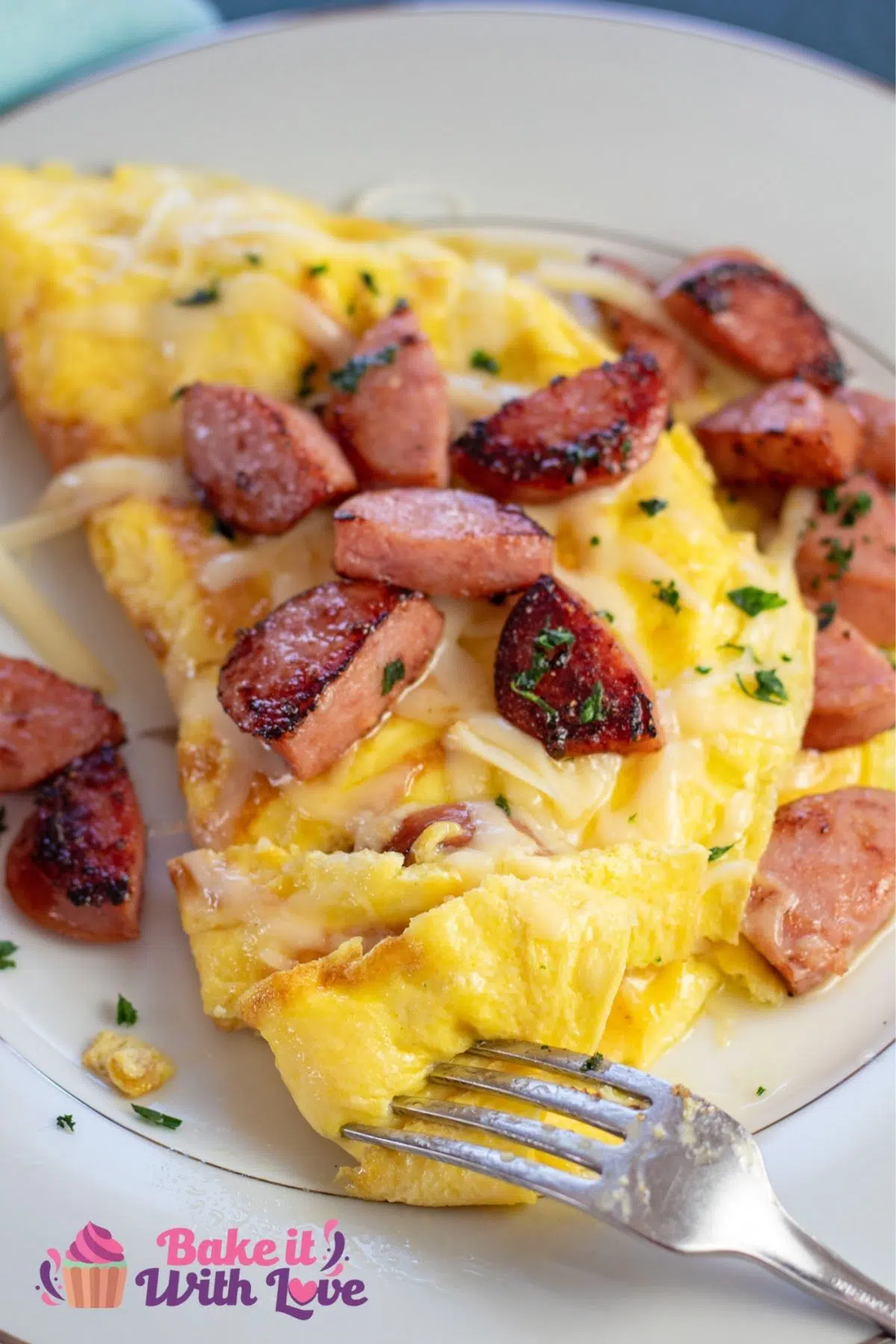 Tall image of kielbasa and Swiss cheese omelet on a white plate.