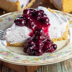 Closeup image of the sliced no-bake blueberry cheesecake on floral plate.