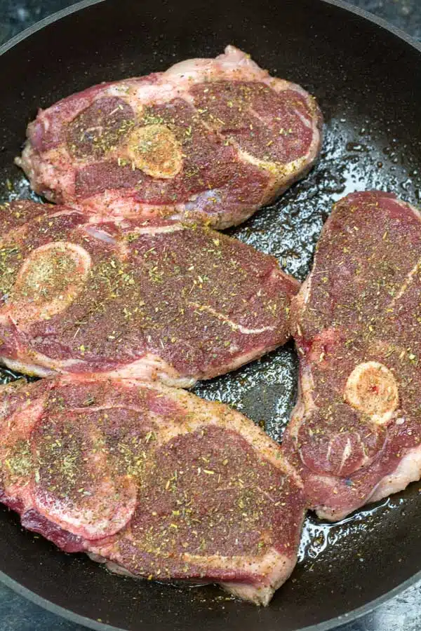 Process photo 1 add seasoned lamb shoulder chops into heated cast iron skillet or frying pan.